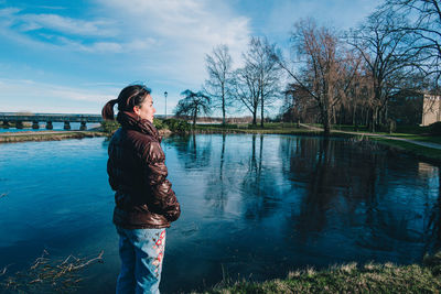 Woman standing by lake against sky