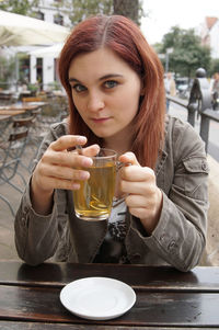 Young woman having drink while sitting at outdoor cafe