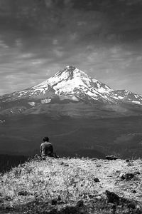 Rear view of man walking on snowcapped mountain against sky