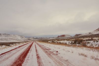 Road leading towards snowcapped mountains against sky