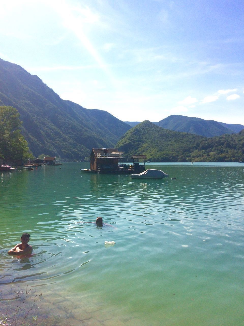 DUCKS SWIMMING IN LAKE AGAINST MOUNTAINS