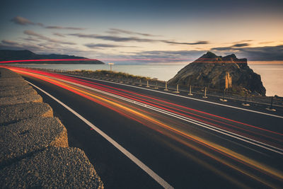 Light trails on road against sky