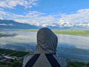 Rear view of woman standing on mountain against sky