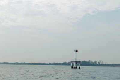 Lighthouse by sea against sky