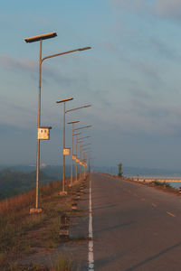 Street lights by road against sky