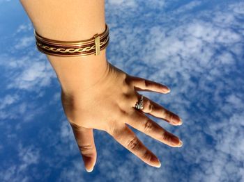 Close-up of woman hand against blue sky