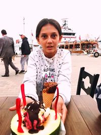 Portrait of young woman with ice cream on table