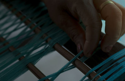 Woman hand holding green cotton strands on weaving machine for weave handmade fabric. textile.