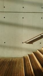 Shadow of wooden railing on hardwood floor against wall