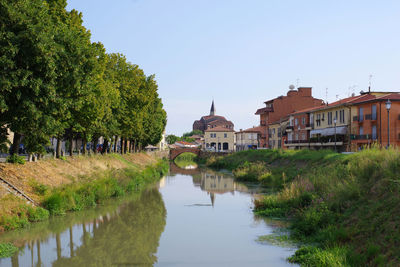 Canal amidst buildings against clear sky