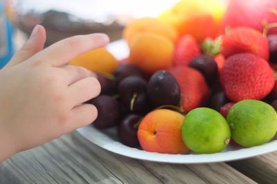 Close-up of hand holding fruits on table