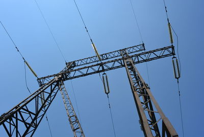 Low angle view of electricity pylon against blue sky