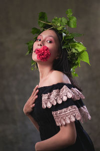 Portrait of young woman standing against plants