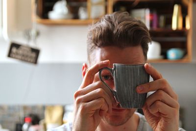 Portrait of young man holding camera at home