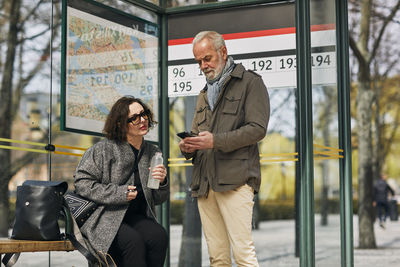 Mature couple using cell phone at bus stop