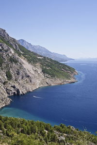 Scenic view of sea and mountains against clear sky