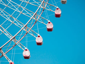 Low angle view of ferris wheel against clear blue sky