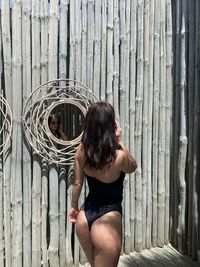 Rear view of woman standing against wooden wall