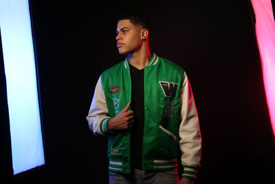 Portrait of young man standing against black background