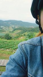 Close-up of woman hand on landscape against sky