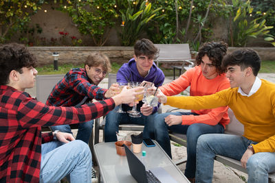 Friends toasting drinks while sitting at cafe