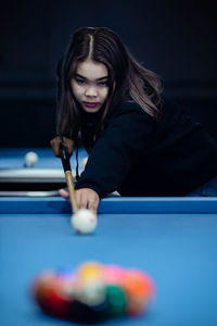 Portrait of young woman playing pool