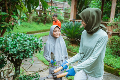 Rear view of young woman standing against plants