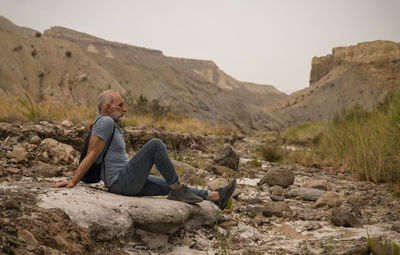 Adult man sitting on rock on tabernas desert in almeria, spain