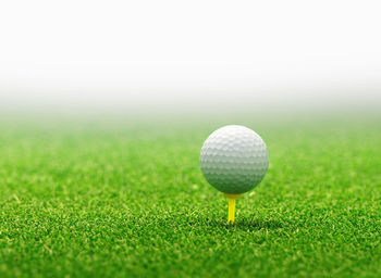 Close-up of golf ball over tee on field