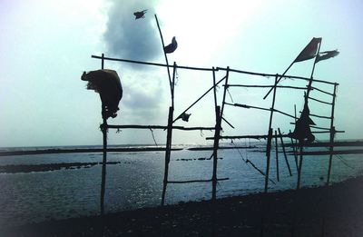 Silhouette men by sea against sky