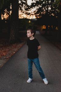 Full length of boy standing on road against trees