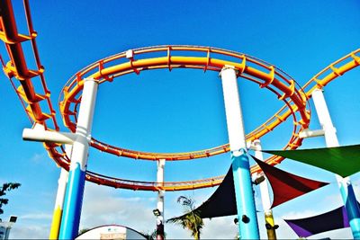 Low angle view of ferris wheel against clear blue sky