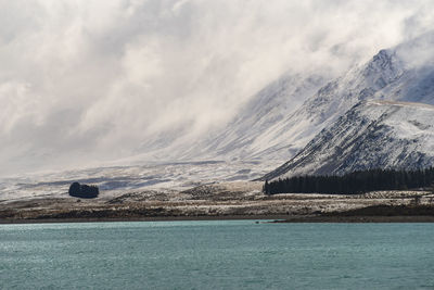 Scenic view of lake by snowcapped mountain against sky