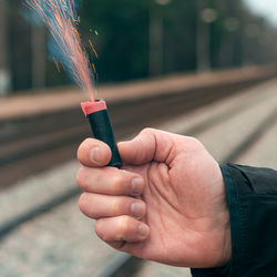 Cropped hand of man holding firecracker