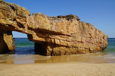 Rock formation on beach against clear sky