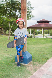 Portrait of boy standing with a skateboard in park