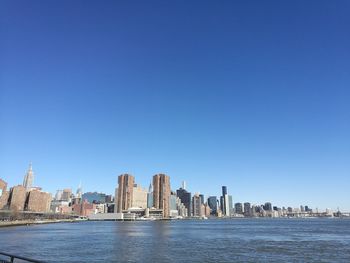 City at waterfront against blue sky