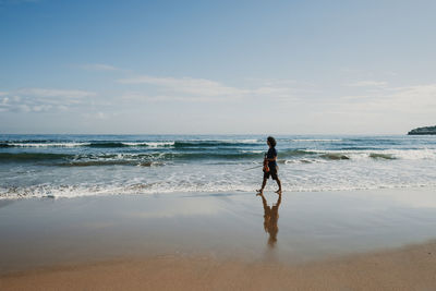 Full length of man standing on beach against sky