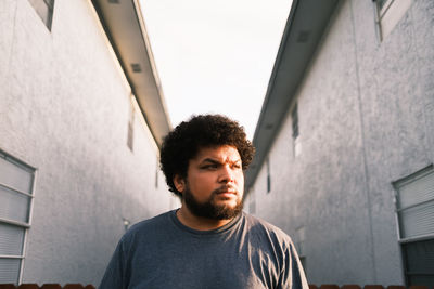 Man looking away while standing against wall