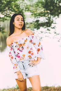 Portrait of young woman standing by lake