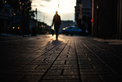 Surface level view of silhouette person walking on footpath during sunset