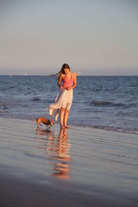 Young woman with dog standing at beach