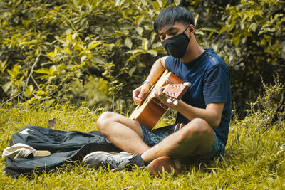 Young man using laptop while sitting on field