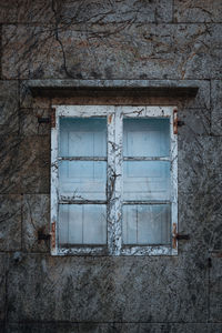 Low angle view of window frame against stone wall