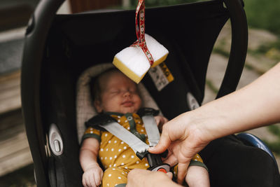 Mother's hands buckling baby in baby swing