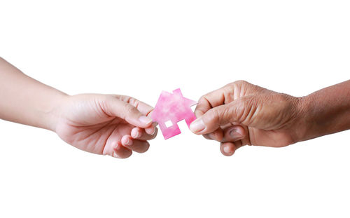 Close-up of hands holding heart shape over white background