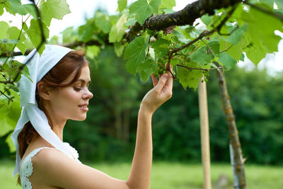 Low angle view of young woman standing against trees