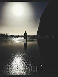 Silhouette man standing at beach against sky