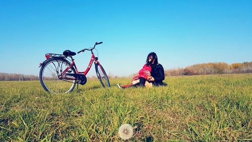 Man with bicycle on field against clear sky