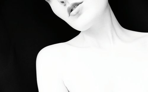 Midsection of naked woman against black background